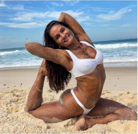Beth Pedote fazendo posição de yoga em praia.
